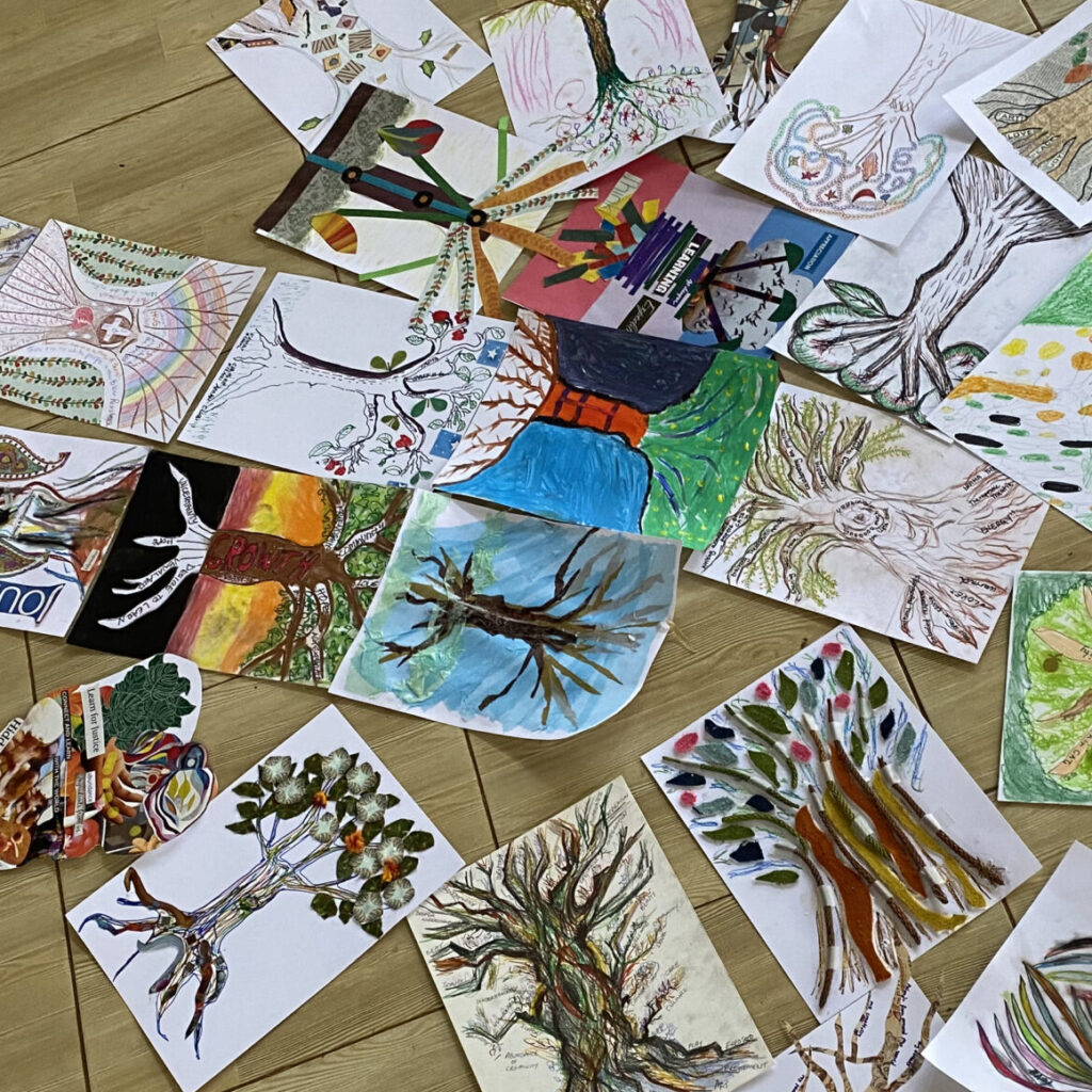 A pile of a dozen art pieces of trees are on the floor