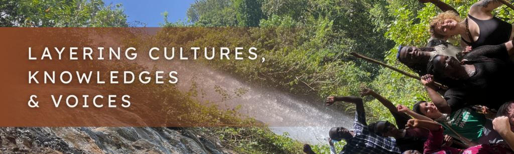 Rotated image of a waterfall, a rock wall and a group of people in the foreground with arms up
